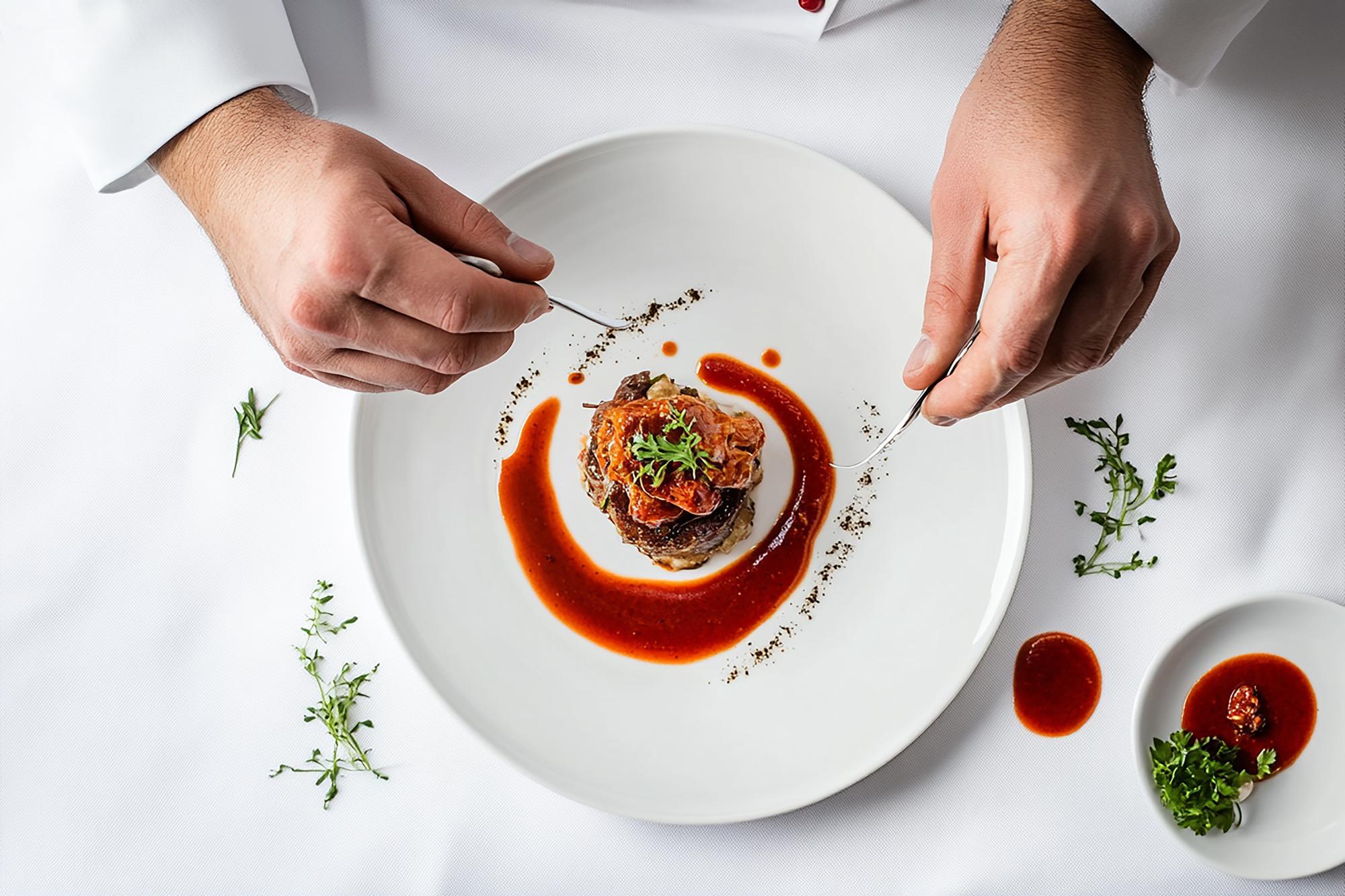 Chef demonstrating plated dish in elegant kitchen